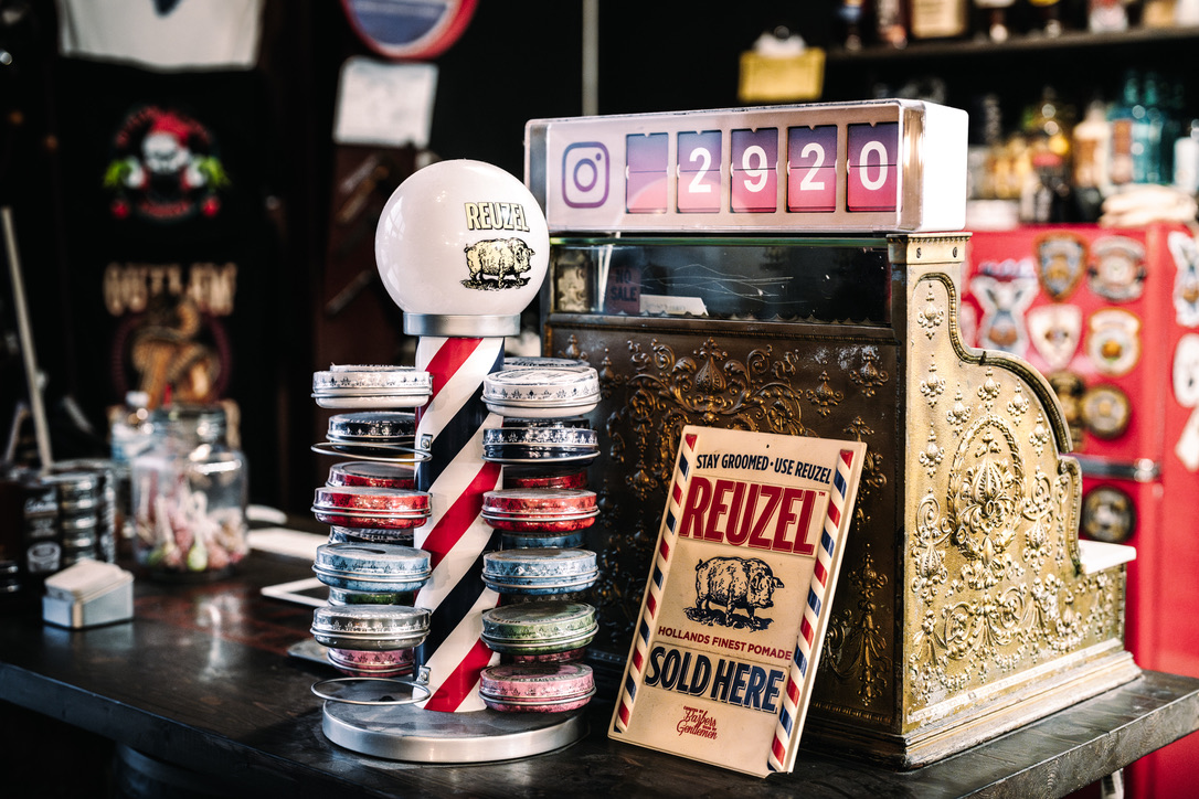 Reuzel pomades displayed beside the vintage register at Outlaw Barber Company